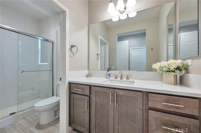 bathroom with a shower stall, toilet, and vanity