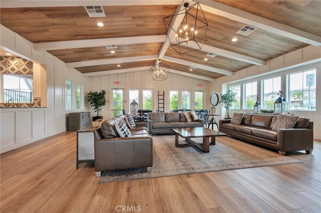 living area featuring a notable chandelier, light wood-style flooring, vaulted ceiling with beams, and visible vents