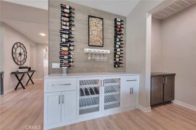 wine room featuring a bar, light wood-style floors, and baseboards