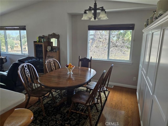 dining area with baseboards, wood finished floors, vaulted ceiling, and a notable chandelier