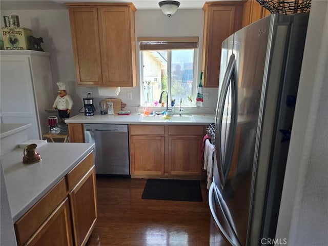 kitchen featuring dark wood-style flooring, light countertops, appliances with stainless steel finishes, a sink, and brown cabinetry