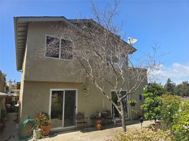 rear view of property featuring stucco siding and a patio
