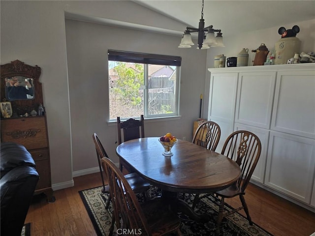 dining area featuring baseboards, lofted ceiling, dark wood-style flooring, and an inviting chandelier