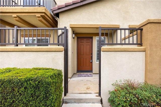 entrance to property featuring stucco siding, a tiled roof, and a balcony