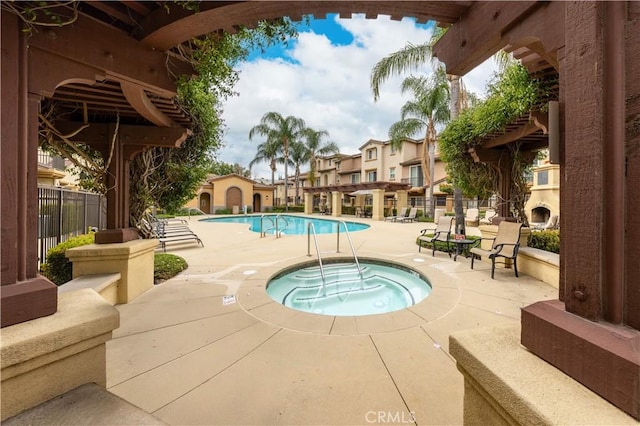 community pool featuring a patio, a community hot tub, fence, and a residential view