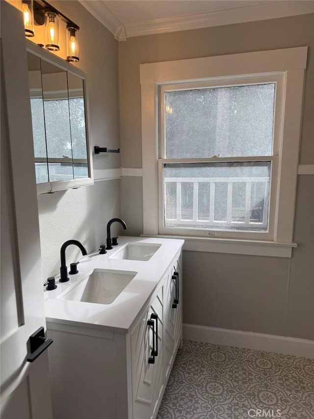 full bath with double vanity, ornamental molding, baseboards, and a sink