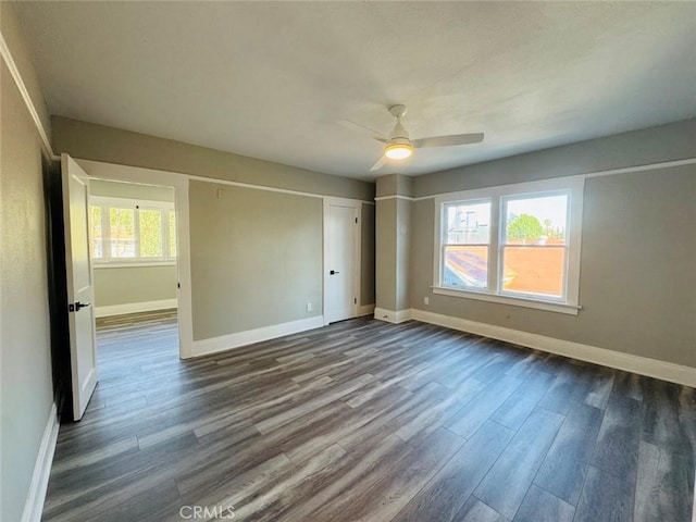 spare room featuring baseboards, dark wood-style floors, and a ceiling fan