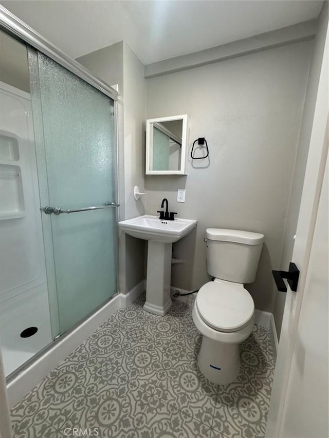 full bathroom with a shower stall, toilet, baseboards, and tile patterned floors