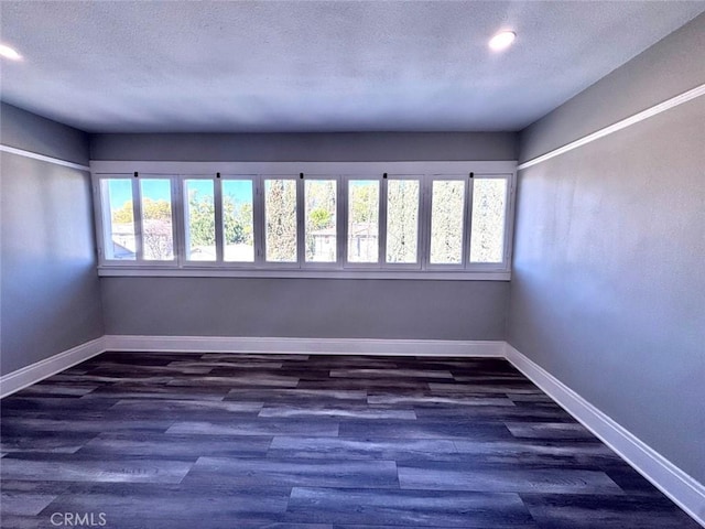 unfurnished room with recessed lighting, baseboards, dark wood-type flooring, and a textured ceiling