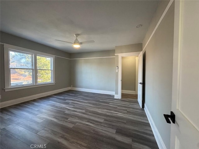 spare room featuring a ceiling fan, dark wood-style floors, and baseboards