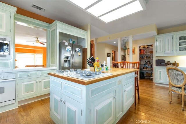 kitchen with visible vents, a center island, ceiling fan, appliances with stainless steel finishes, and light wood-style floors