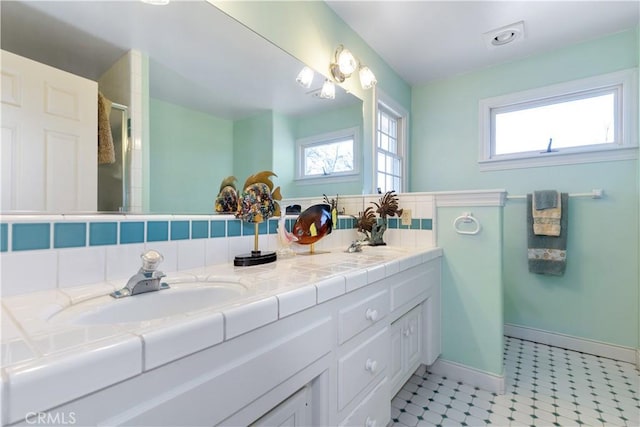 bathroom featuring double vanity, plenty of natural light, a stall shower, and a sink