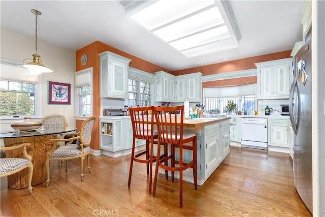 kitchen featuring light wood finished floors, dishwasher, white cabinetry, and light countertops