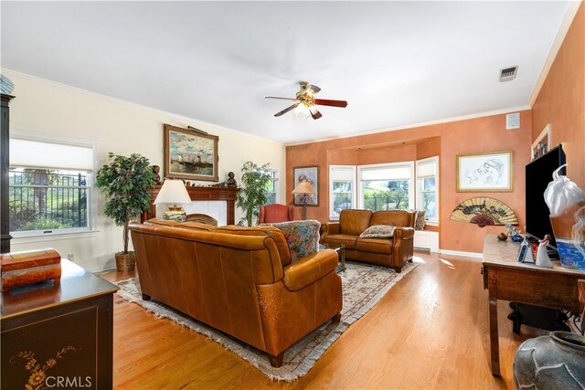 living room featuring light wood finished floors, a ceiling fan, and a wealth of natural light