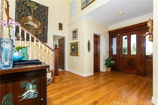foyer entrance featuring stairs, light wood-style floors, baseboards, and ornamental molding