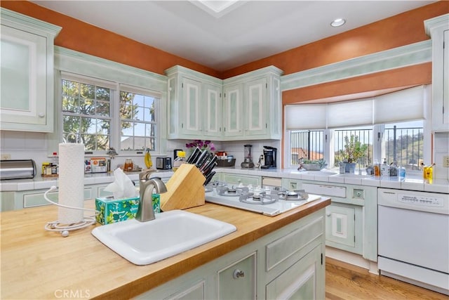 kitchen featuring white appliances, wooden counters, a sink, glass insert cabinets, and light wood-type flooring