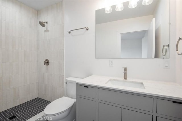 full bathroom with toilet, vanity, and a tile shower