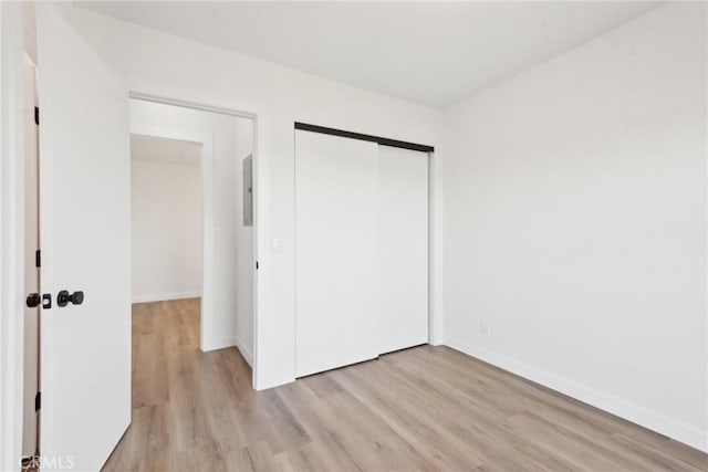 unfurnished bedroom featuring a closet, baseboards, and light wood-style flooring