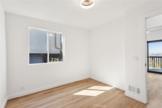 empty room featuring wood finished floors, visible vents, and baseboards