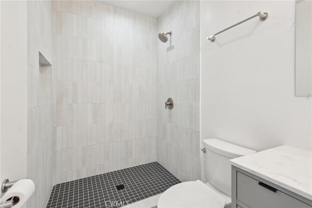 full bathroom with vanity, toilet, and a tile shower