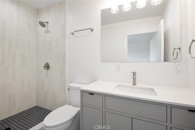 bathroom featuring toilet, vanity, and a tile shower