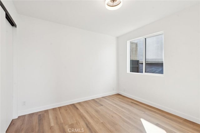 spare room with light wood-type flooring and baseboards