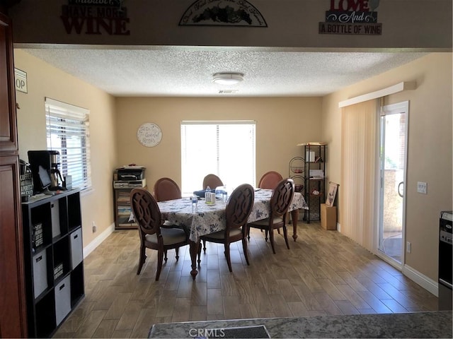 dining area featuring a wealth of natural light, dark wood-type flooring, and a textured ceiling