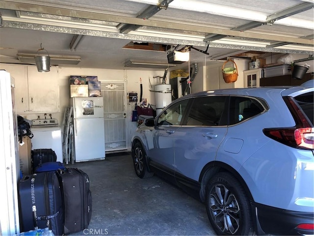 garage featuring strapped water heater, washer and dryer, a garage door opener, and freestanding refrigerator