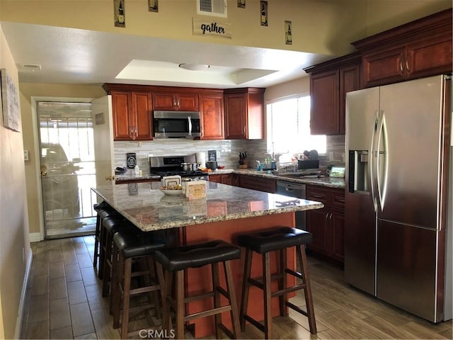 kitchen featuring stainless steel appliances, a kitchen breakfast bar, tasteful backsplash, and wood finished floors