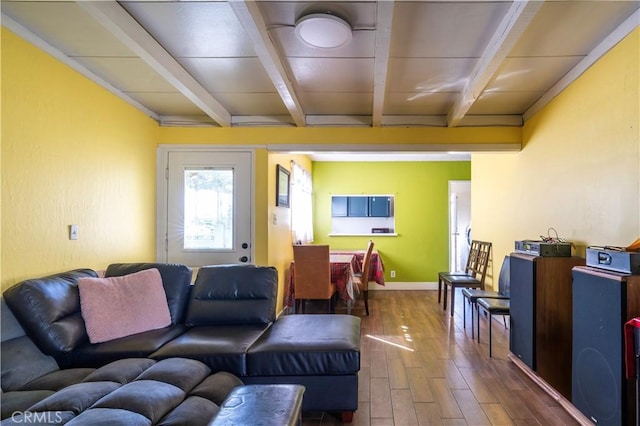 living area featuring baseboards, beam ceiling, and wood finished floors