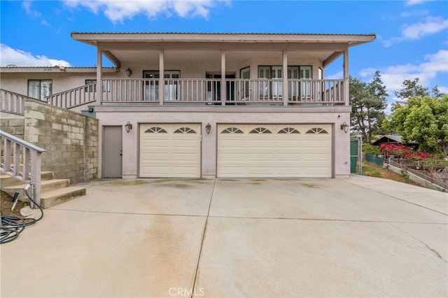 view of front of property featuring stairs, a garage, driveway, and stucco siding