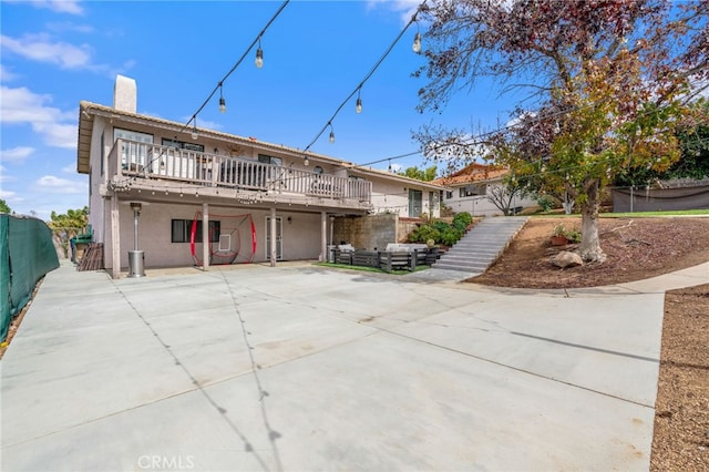 rear view of house with a patio, fence, stucco siding, stairs, and a chimney