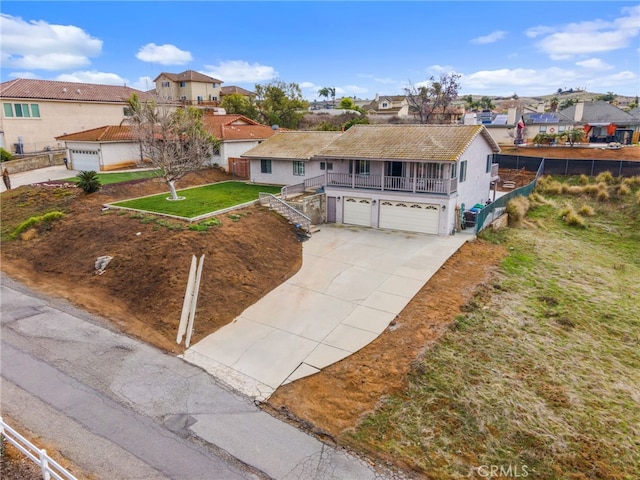 view of front of property featuring a residential view, an attached garage, concrete driveway, and fence