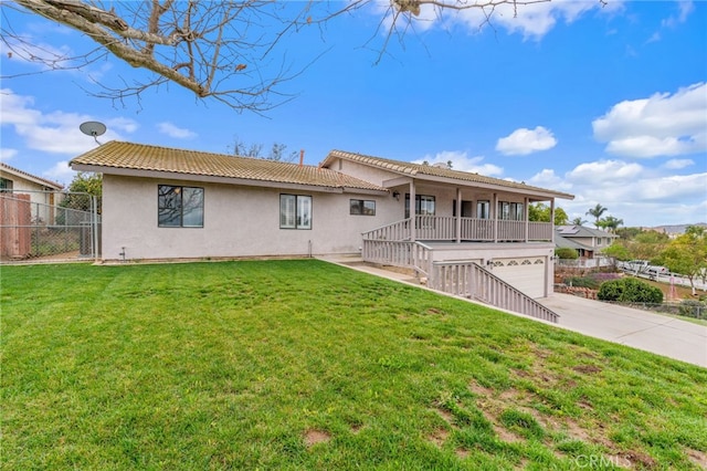 rear view of property featuring a tiled roof, concrete driveway, stucco siding, a garage, and a yard