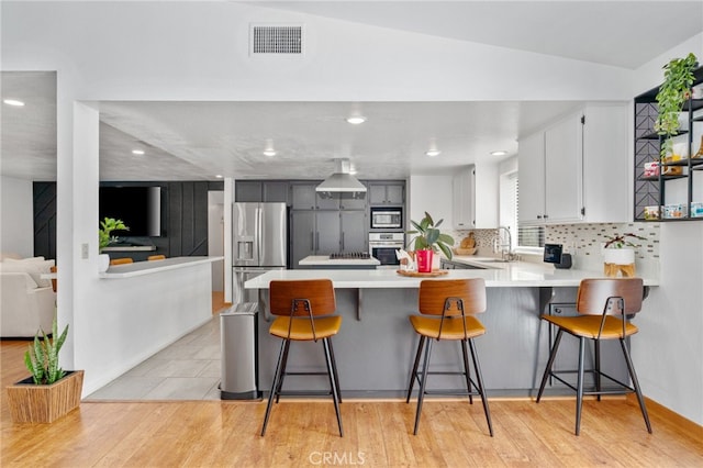 kitchen with a peninsula, light wood-style floors, visible vents, and stainless steel appliances