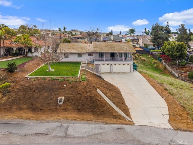 view of front facade with fence, an attached garage, concrete driveway, a front lawn, and a residential view