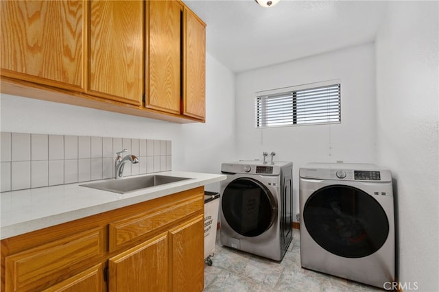 laundry area with cabinet space, independent washer and dryer, and a sink