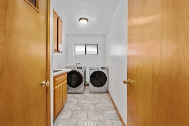 washroom featuring baseboards, cabinet space, stone finish floor, a textured ceiling, and washer and dryer