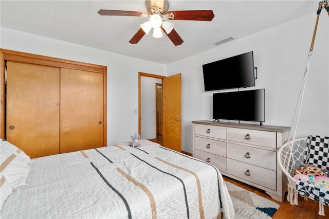 bedroom with wood finished floors, visible vents, a closet, and ceiling fan