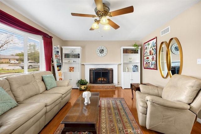 living area with visible vents, ceiling fan, and wood finished floors