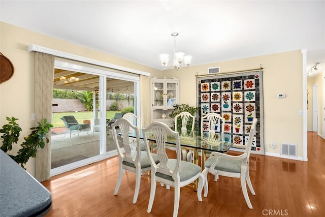 dining area featuring visible vents, baseboards, an inviting chandelier, and wood finished floors