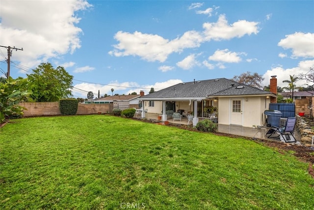 rear view of house with a lawn, a fenced backyard, and a patio area