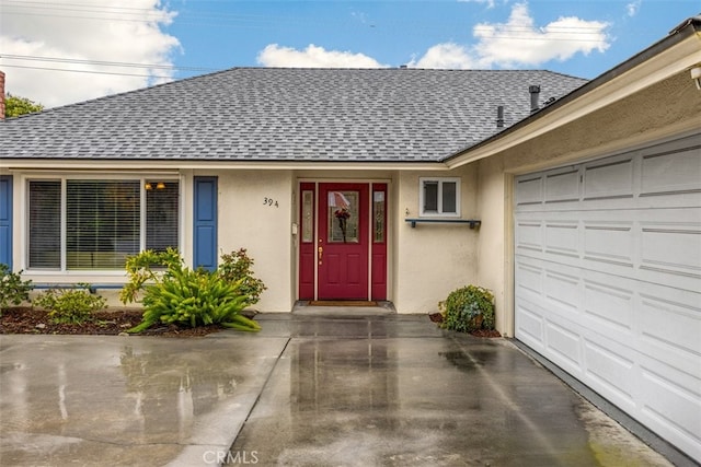 doorway to property featuring stucco siding, an attached garage, and a shingled roof