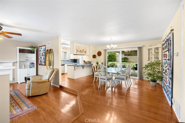 dining area with visible vents, wood finished floors, and ceiling fan with notable chandelier