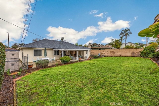 back of property with a yard, stucco siding, a patio, and a fenced backyard