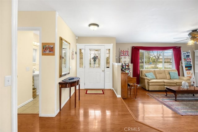 foyer entrance featuring ceiling fan, baseboards, and wood finished floors