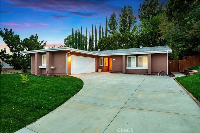 ranch-style house with concrete driveway, an attached garage, a yard, and stucco siding