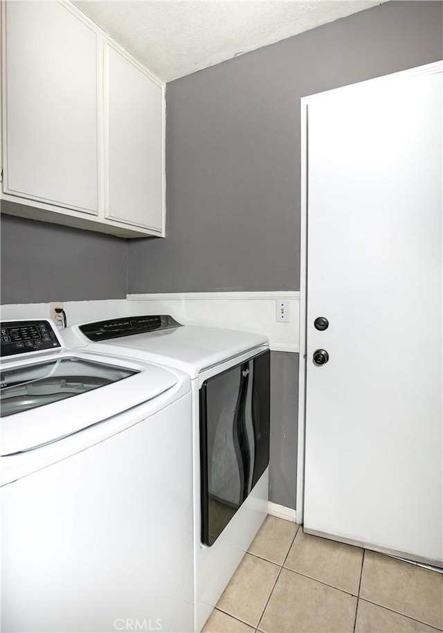 laundry room with light tile patterned flooring, cabinet space, and washer and dryer