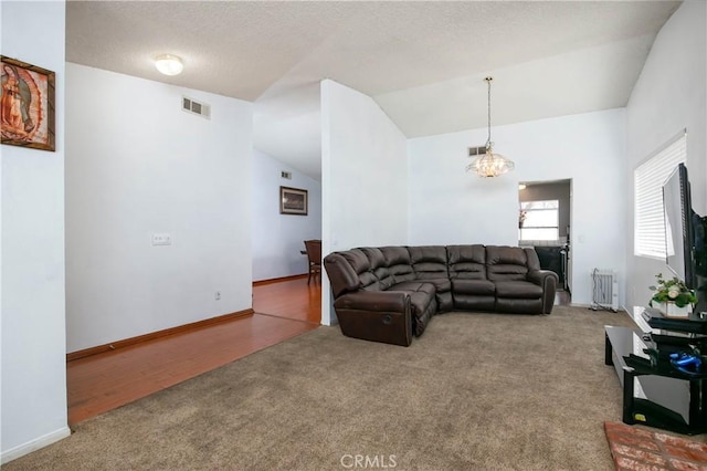 living room featuring visible vents, a textured ceiling, carpet floors, radiator, and vaulted ceiling