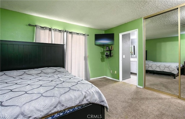 bedroom featuring carpet, baseboards, ensuite bath, a closet, and a textured ceiling